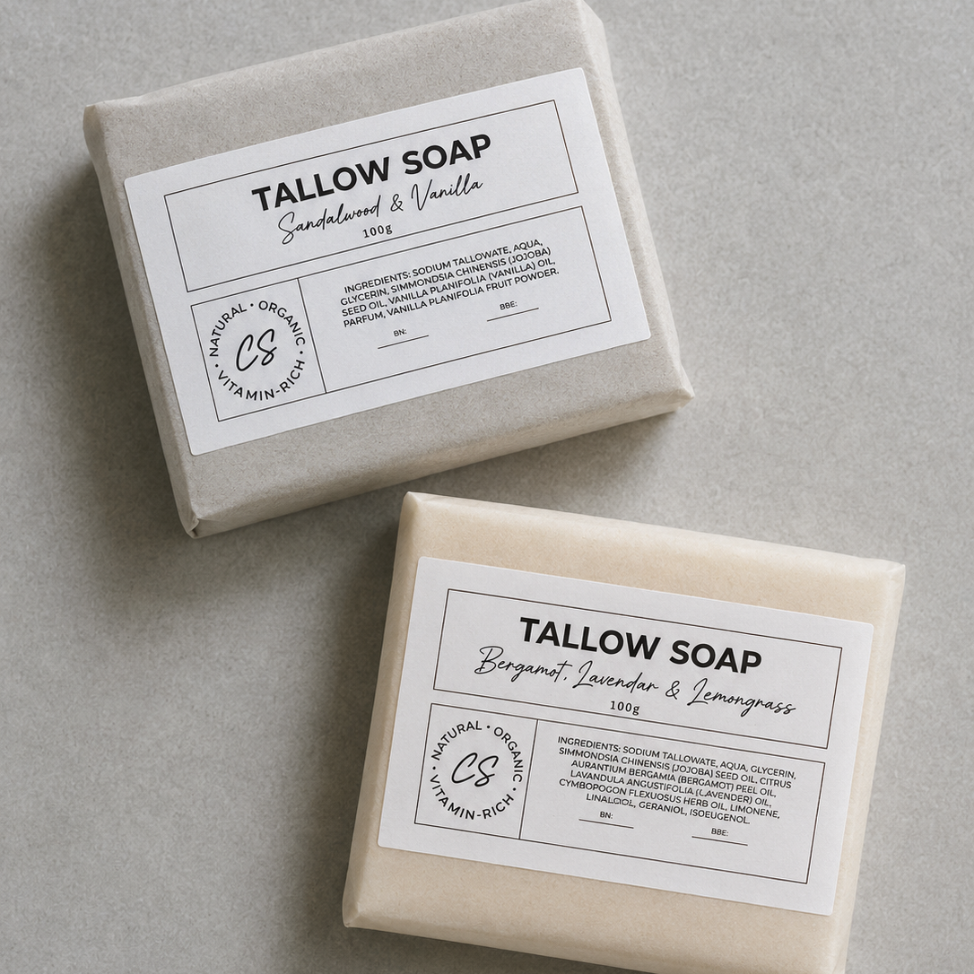 Two wrapped bars of Tallow Soap on a neutral gray background, one labeled Sandalwood & Vanilla and the other Bergamot & Lemongrass, both with white paper labels showing ingredients and a circular CS logo.