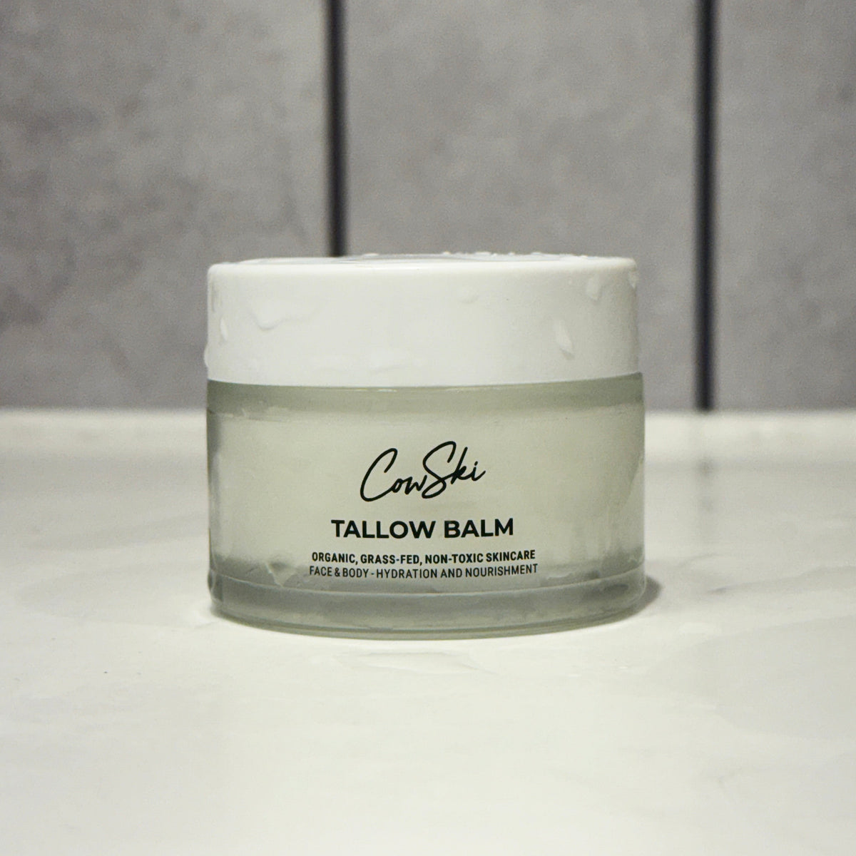 Jar of tallow balm with 'CowSki' branding on a neutral background